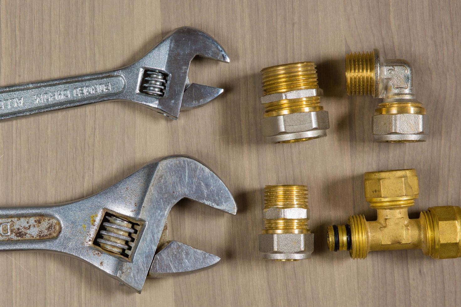 Different tools on a wooden background. Adjustable wrench and parts for plumbing photo