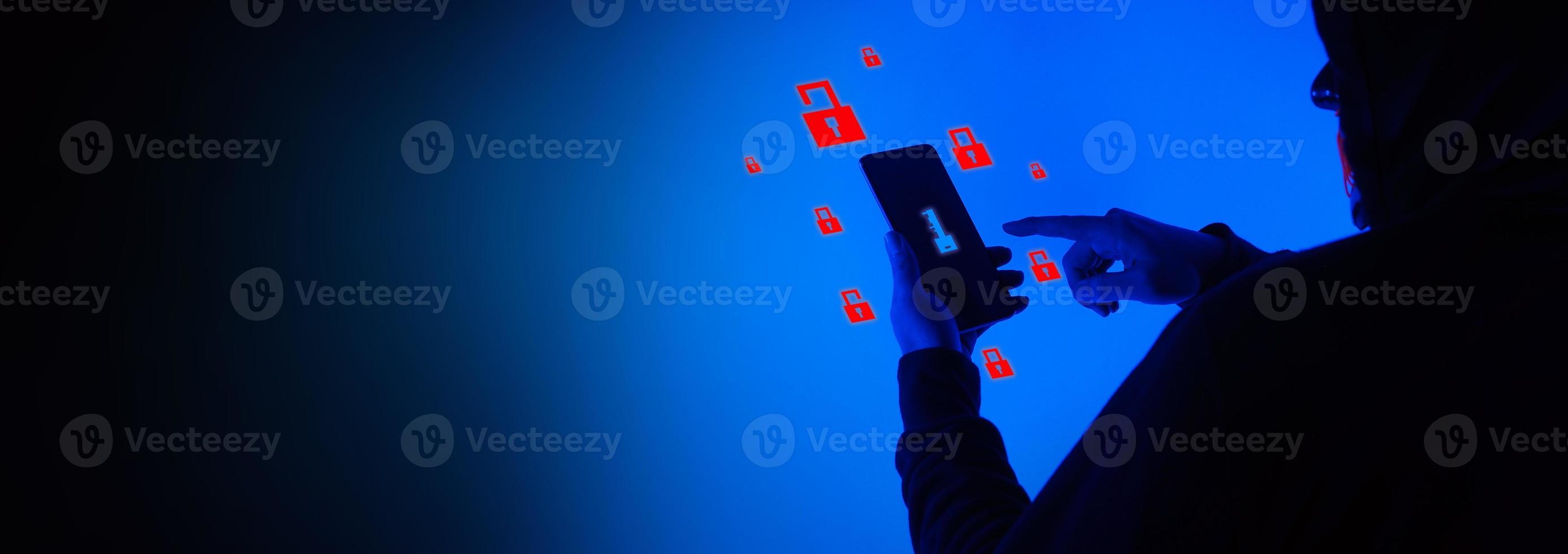 Digital security Concept. Anonymous hacker with mask holding smartphone hacked. photo