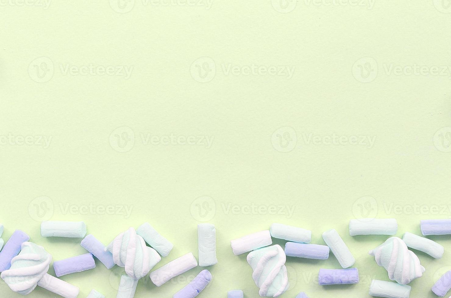 Colorful marshmallow laid out on lime paper background. pastel creative textured framework photo