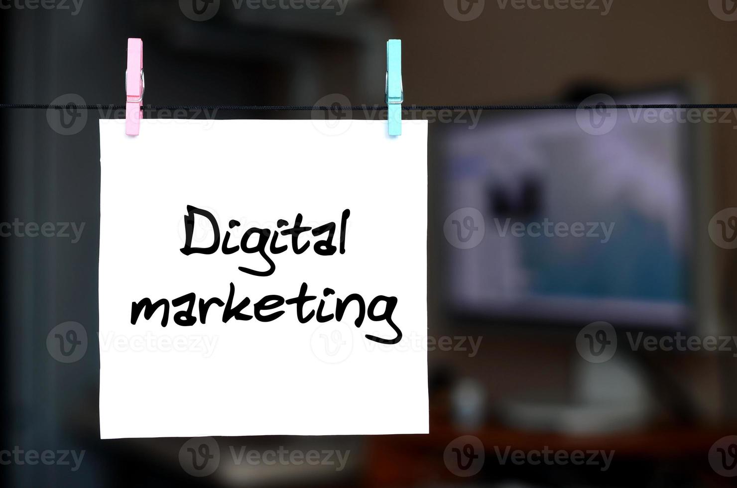 Digital marketing. Note is written on a white sticker that hangs with a clothespin on a rope on a background of office interior photo
