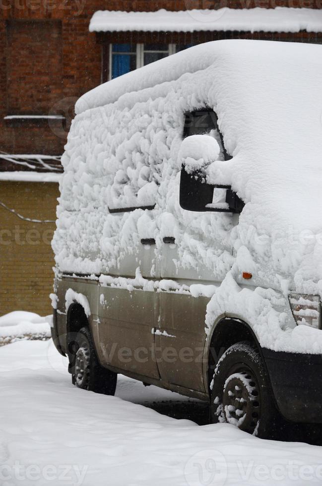 Fragment of the car under a layer of snow after a heavy snowfall. The body of the car is covered with white snow photo