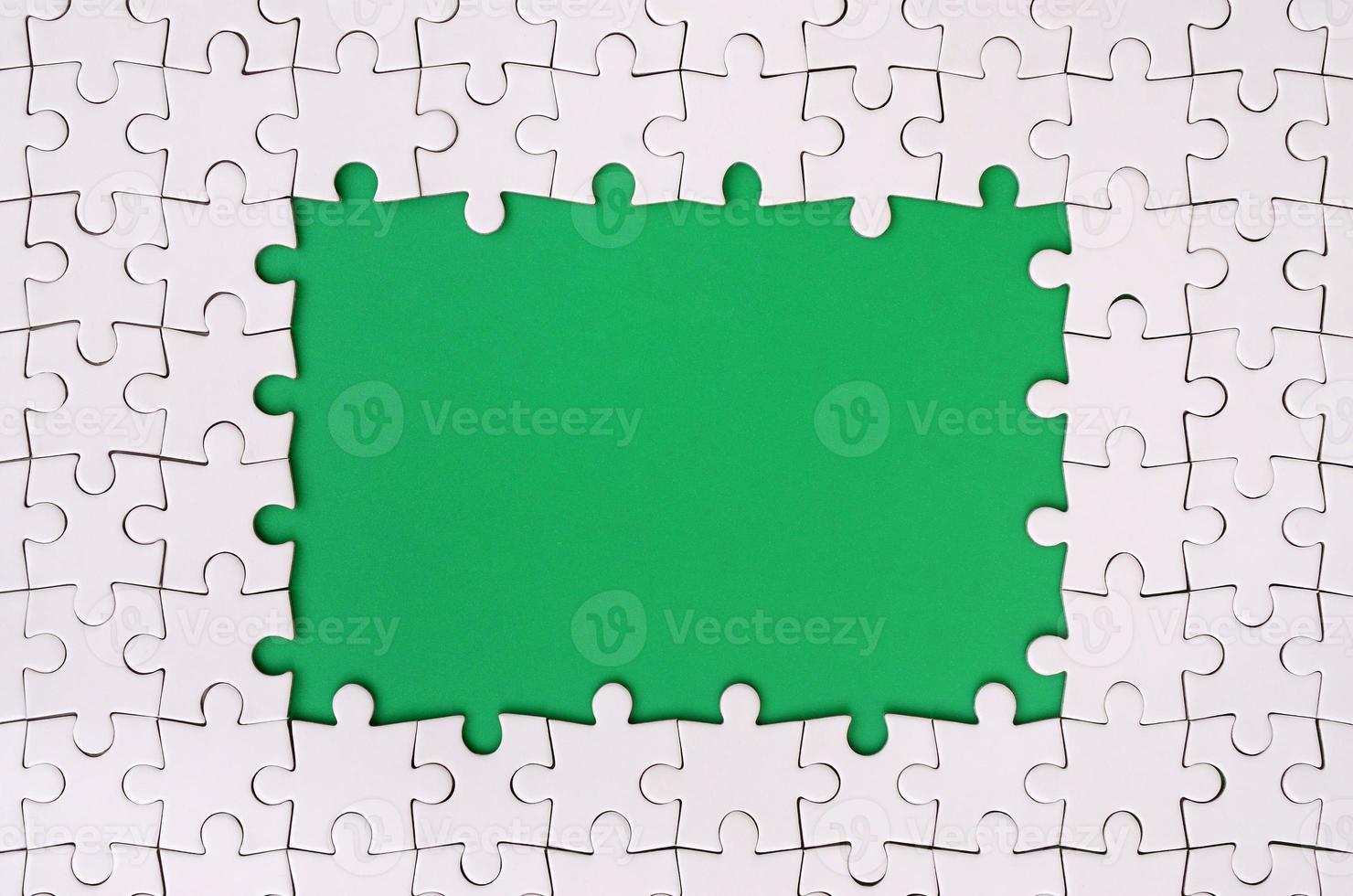 Framing in the form of a rectangle, made of a white jigsaw puzzle around the green space photo