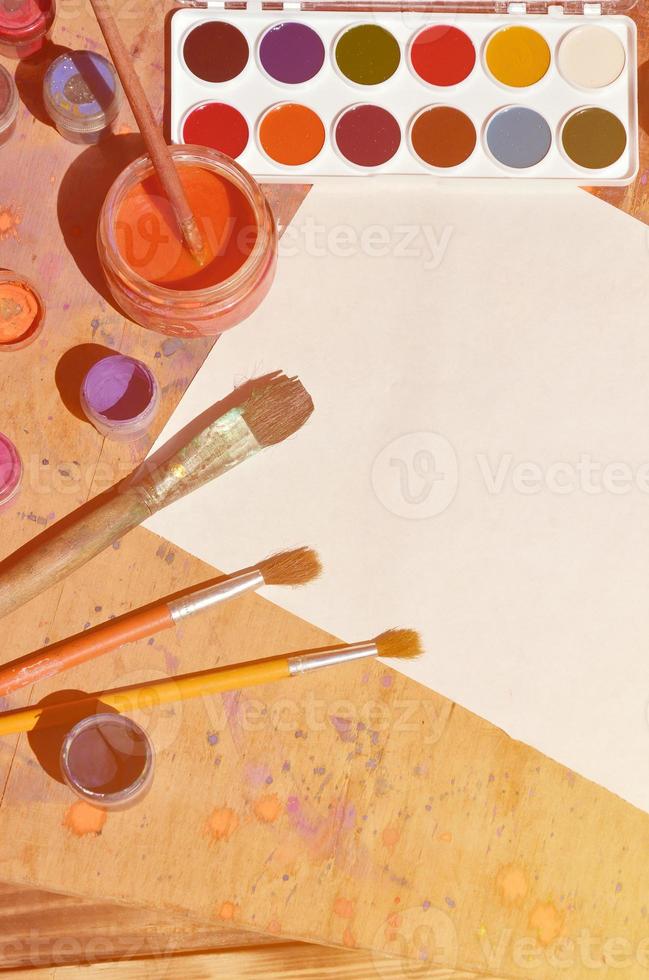 Still life with blank paper, brushes and jars of watercolor and gouache paint photo