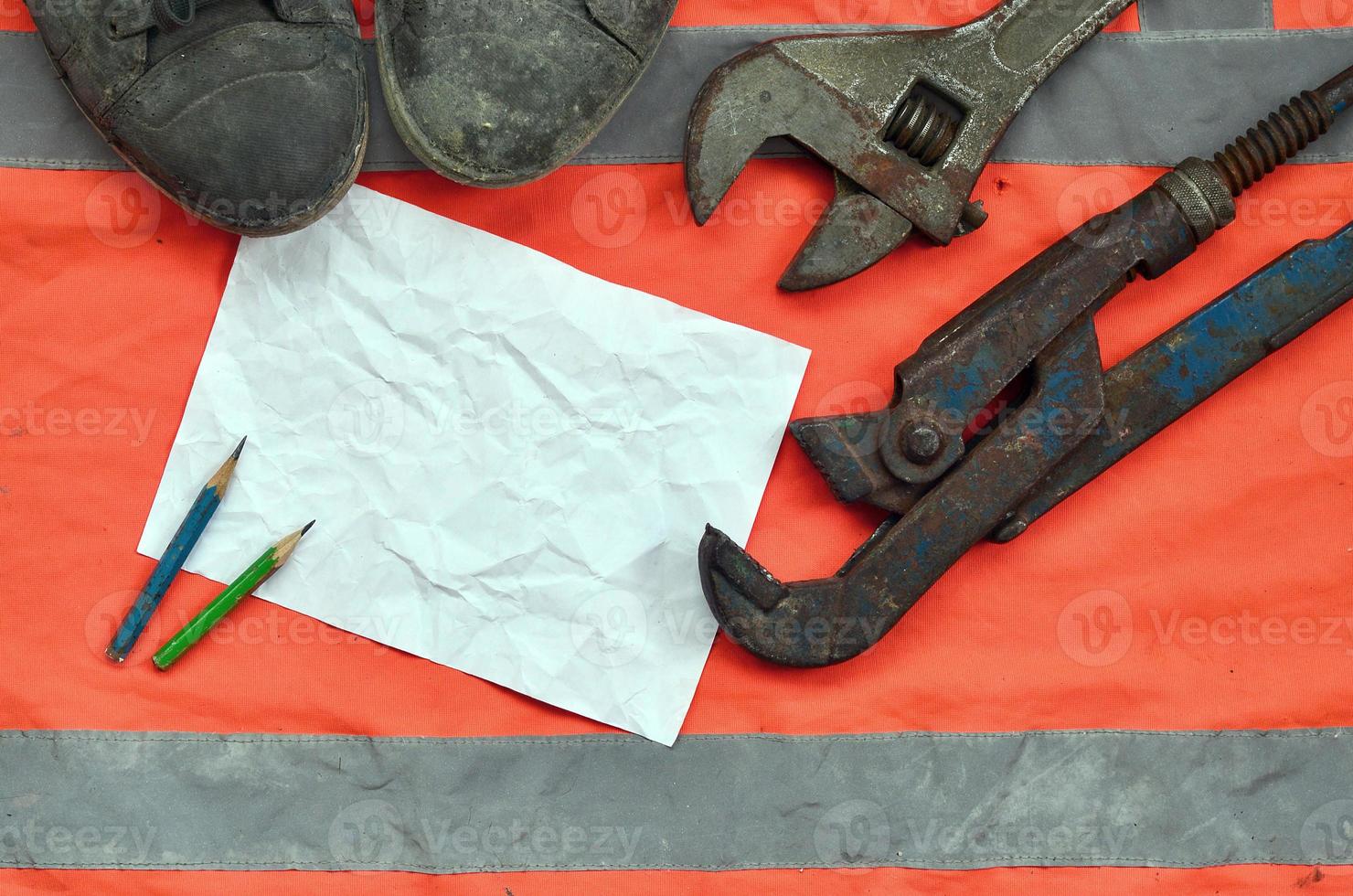 Adjustable wrenches with old boots and a sheet of paper with two pencils photo