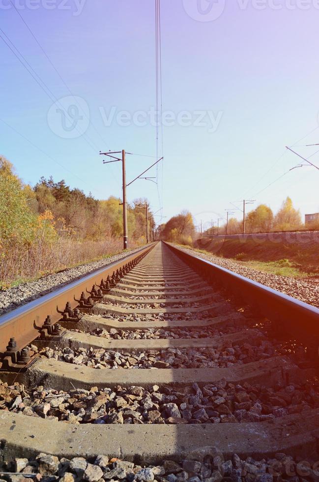 Autumn industrial landscape. Railway receding into the distance among green and yellow autumn trees photo