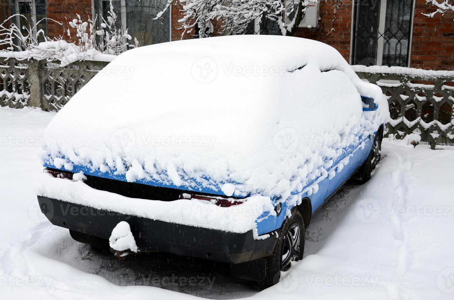 Photo of a car covered in a thick layer of snow. Consequences of heavy snowfall