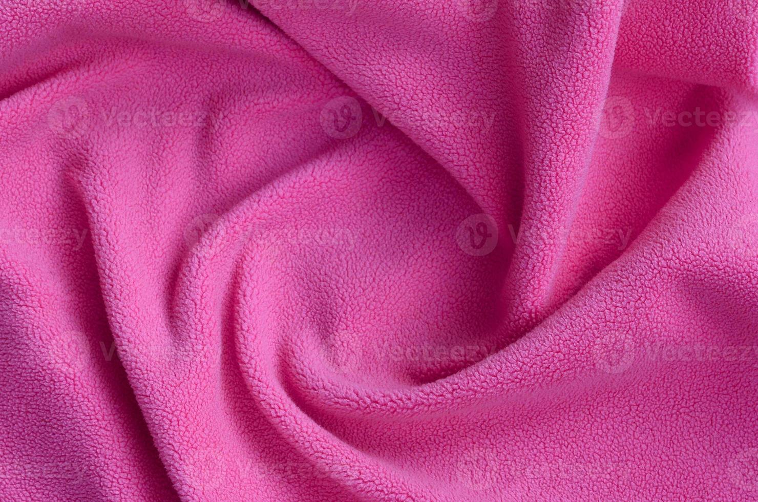 The blanket of furry pink fleece fabric. A background of light pink soft plush fleece material with a lot of relief folds photo