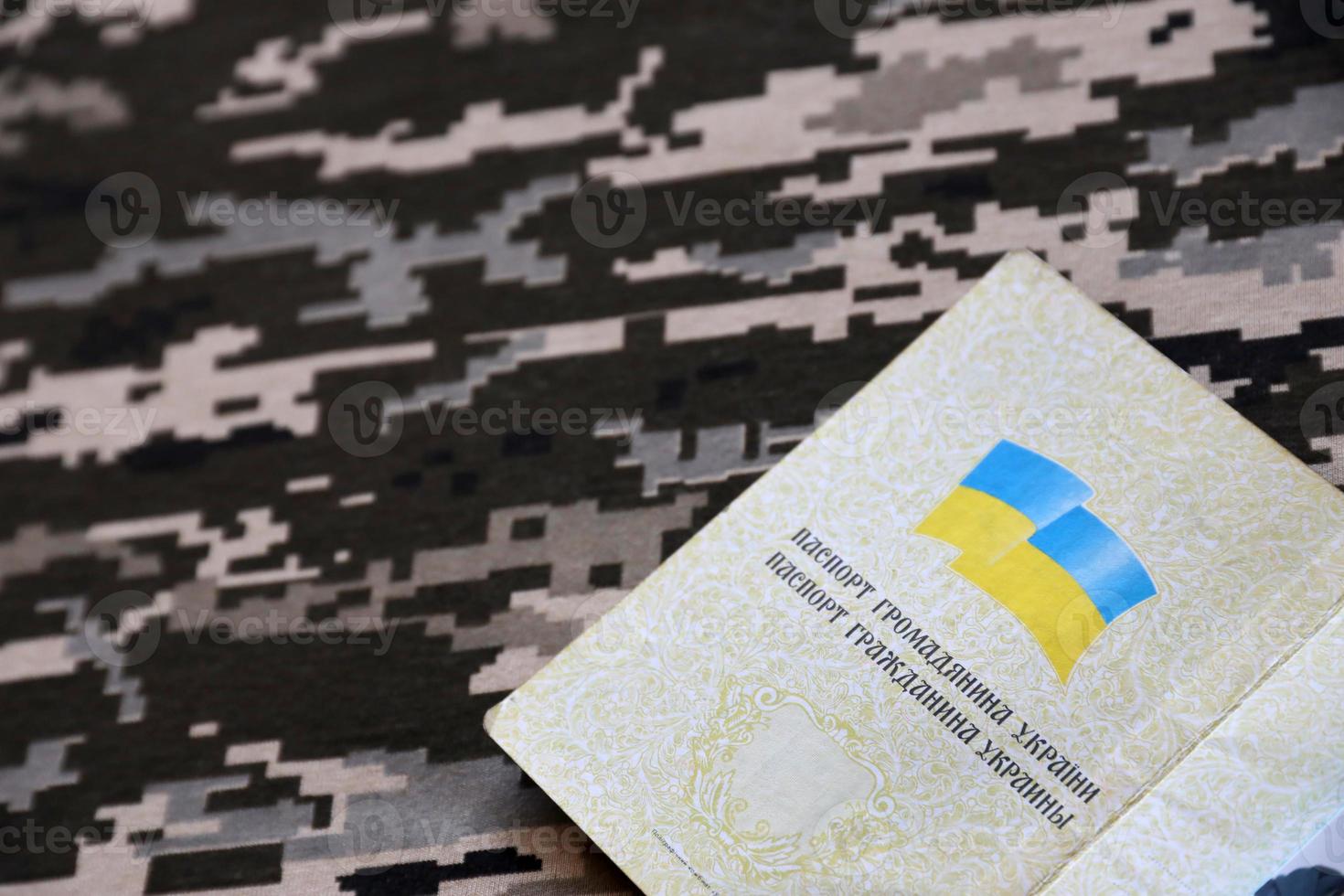 pasaporte extranjero ucraniano sobre tela con textura de camuflaje militar pixelado. tela con patrón de camuflaje en formas de píxeles grises, marrones y verdes e identificación ucraniana foto