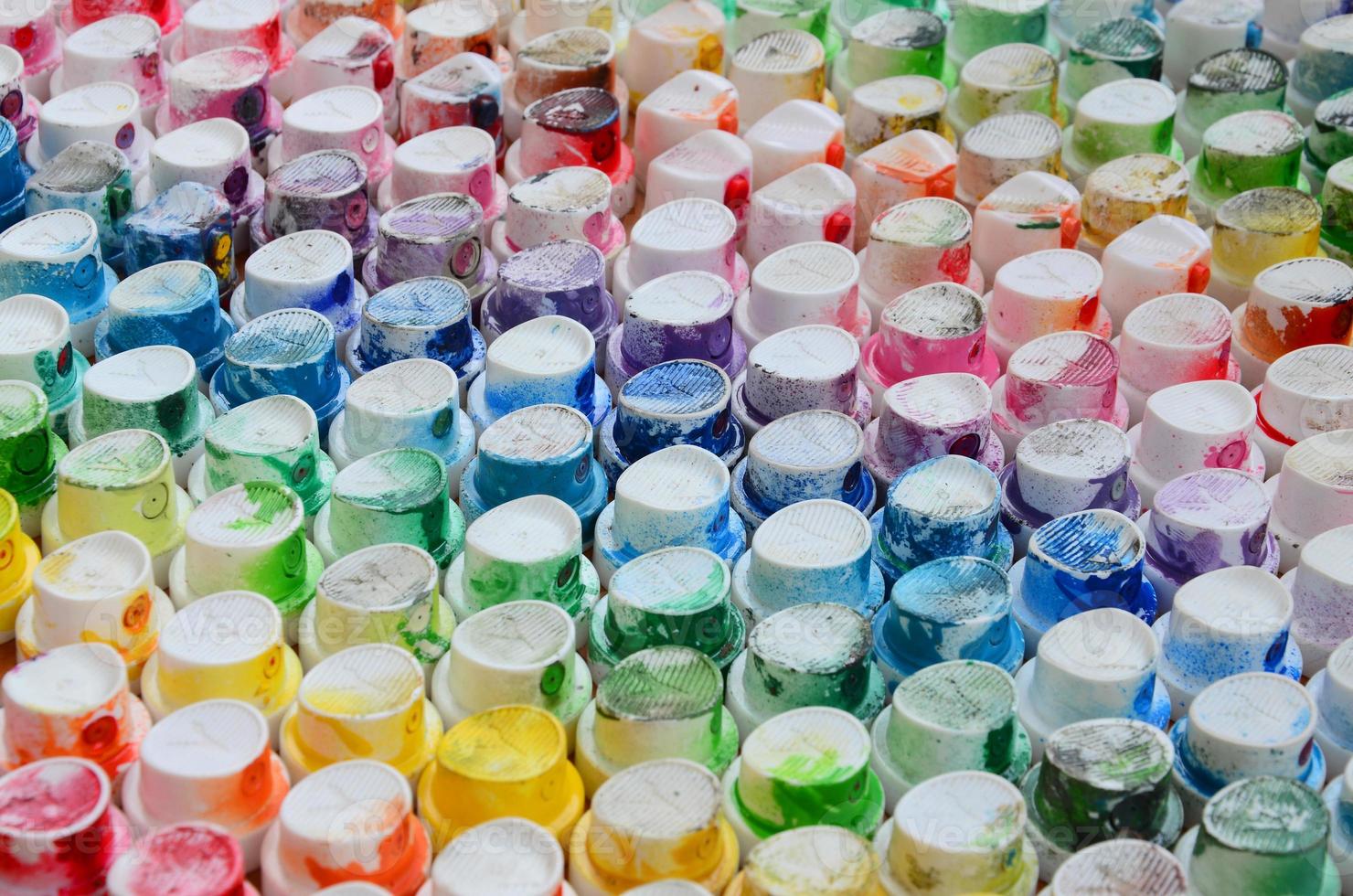 A pattern from a many nozzles from a paint sprayer for drawing graffiti, smeared into different colors. The plastic caps are arranged in many rows forming the color of the rainbow photo