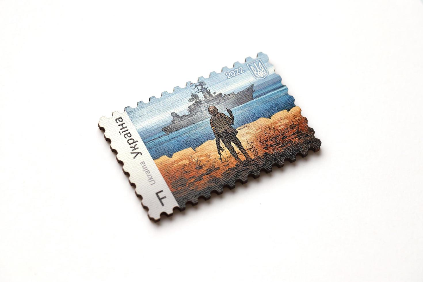 TERNOPIL, UKRAINE - SEPTEMBER 2, 2022 Famous Ukrainian postmark with russian warship and ukrainian soldier as wooden souvenir on white background photo