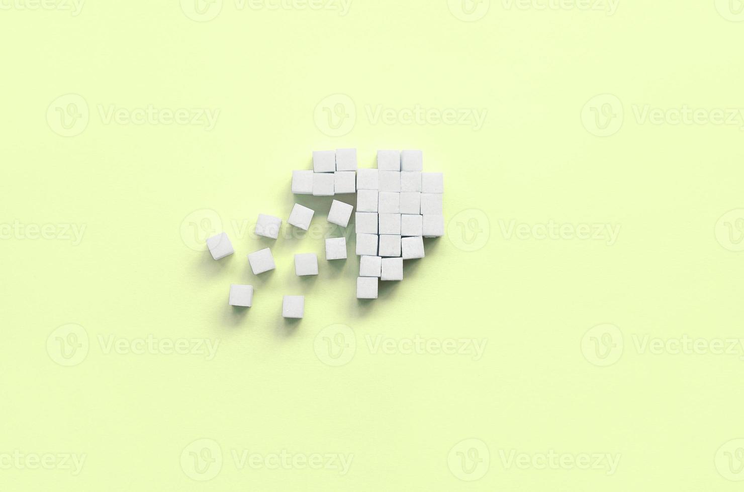 A broken heart made of sugar cubes lies on a trendy pastel lime photo