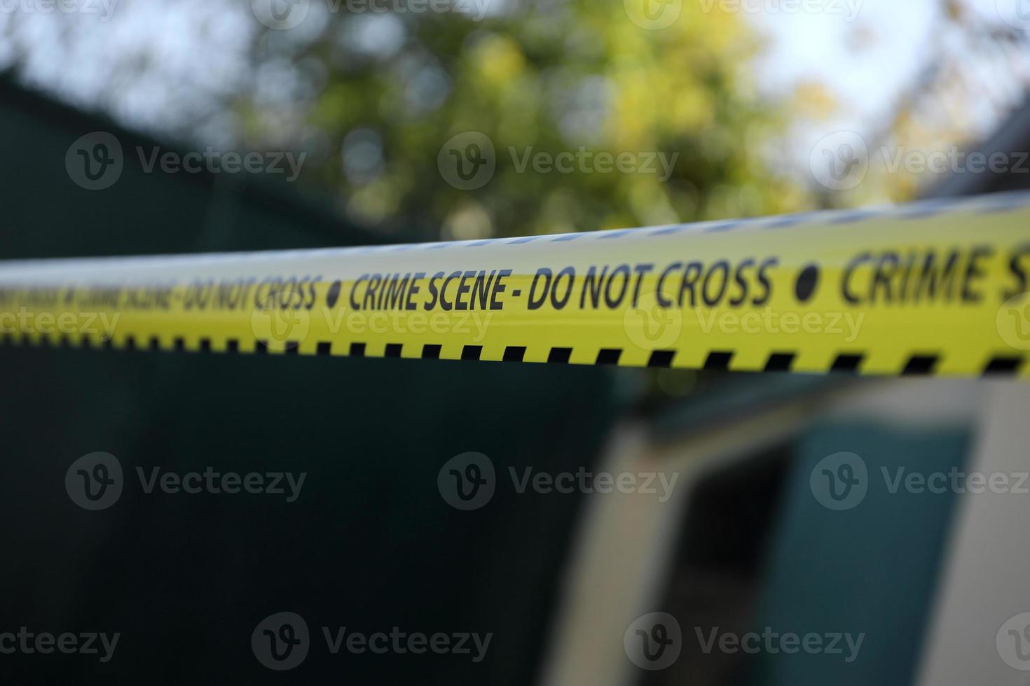 Crime scene tape for covering the area cordon. Yellow tape with blurred forensic law enforcement background in cinematic tone photo