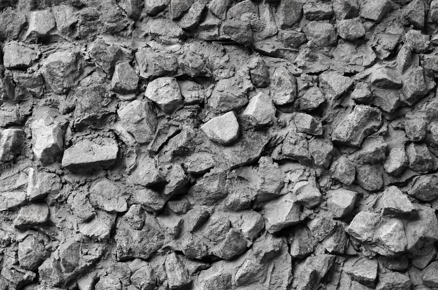 The texture of a strong stone wall of many concreted stones of various shapes photo