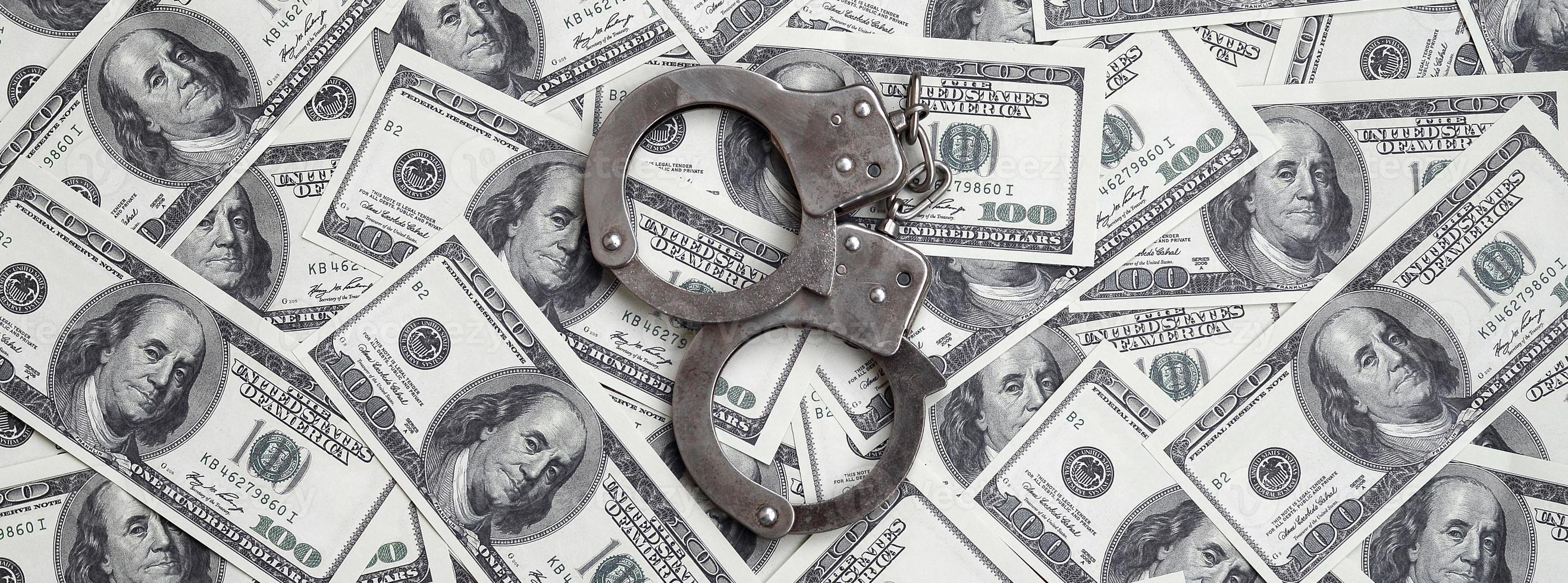 Police handcuffs lie on a lot of dollar bills. The concept of illegal possession of money, illegal transactions with US dollars. Economic Crime photo