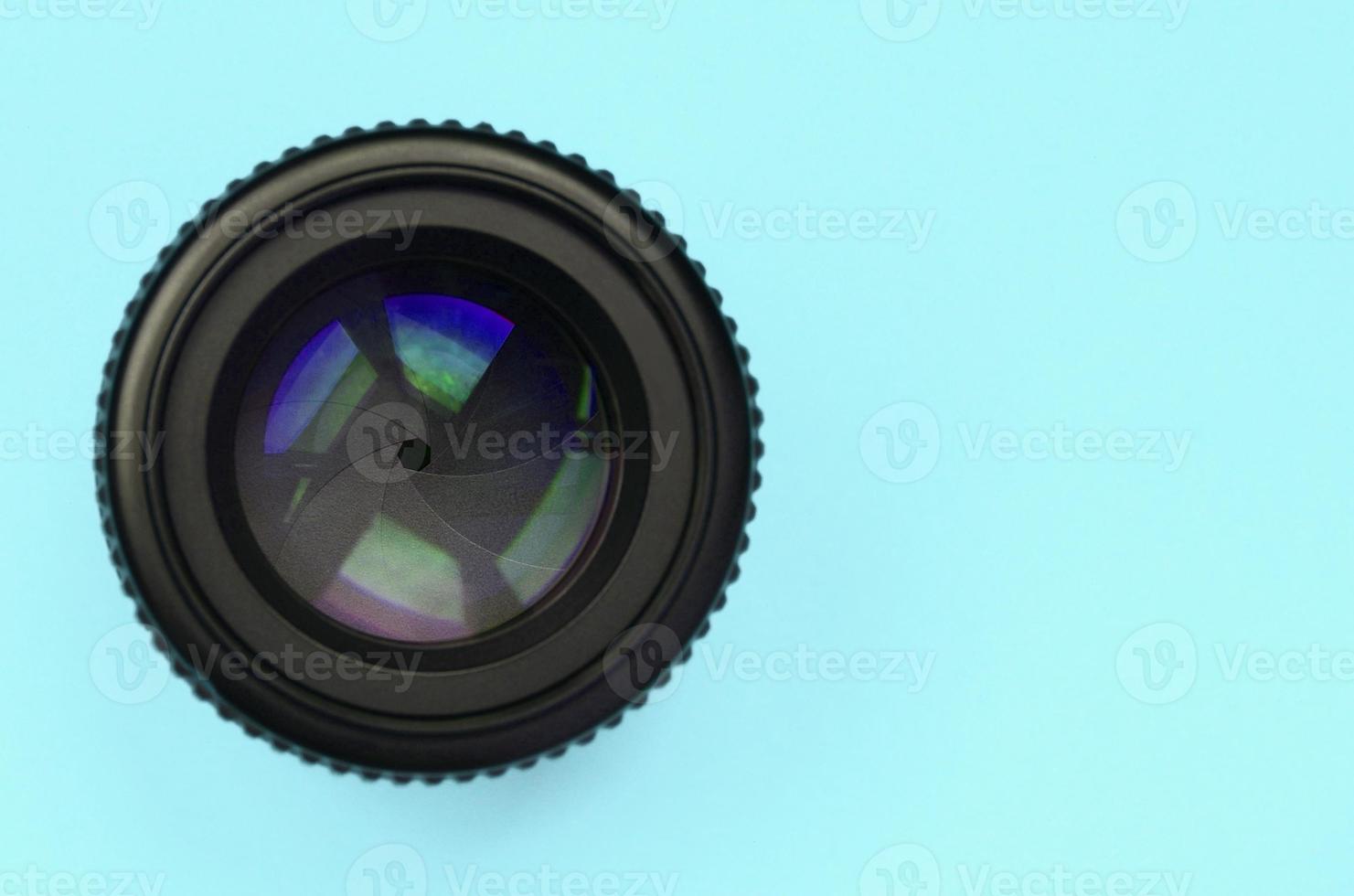 Camera lens with a closed aperture lie on texture background of fashion pastel blue color paper photo