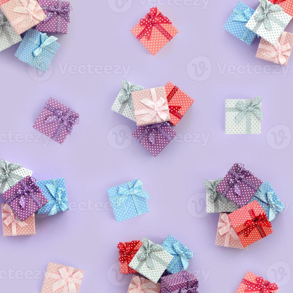 Piles of a small colored gift boxes with ribbons lies on a violet background. Minimalism flat lay top view pattern photo