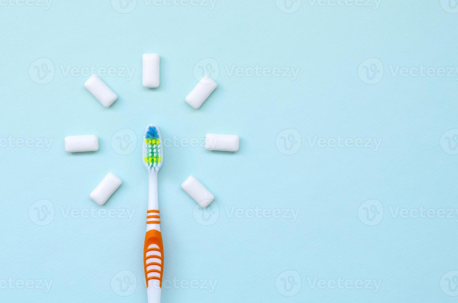 Toothbrush and chewing gums lie on a pastel blue background. Top view, flat lay. Minimal concept photo