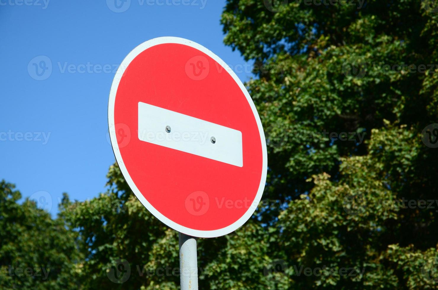 A circular red sign with a white bar indicating NO ENTRY on a grey metal post photo