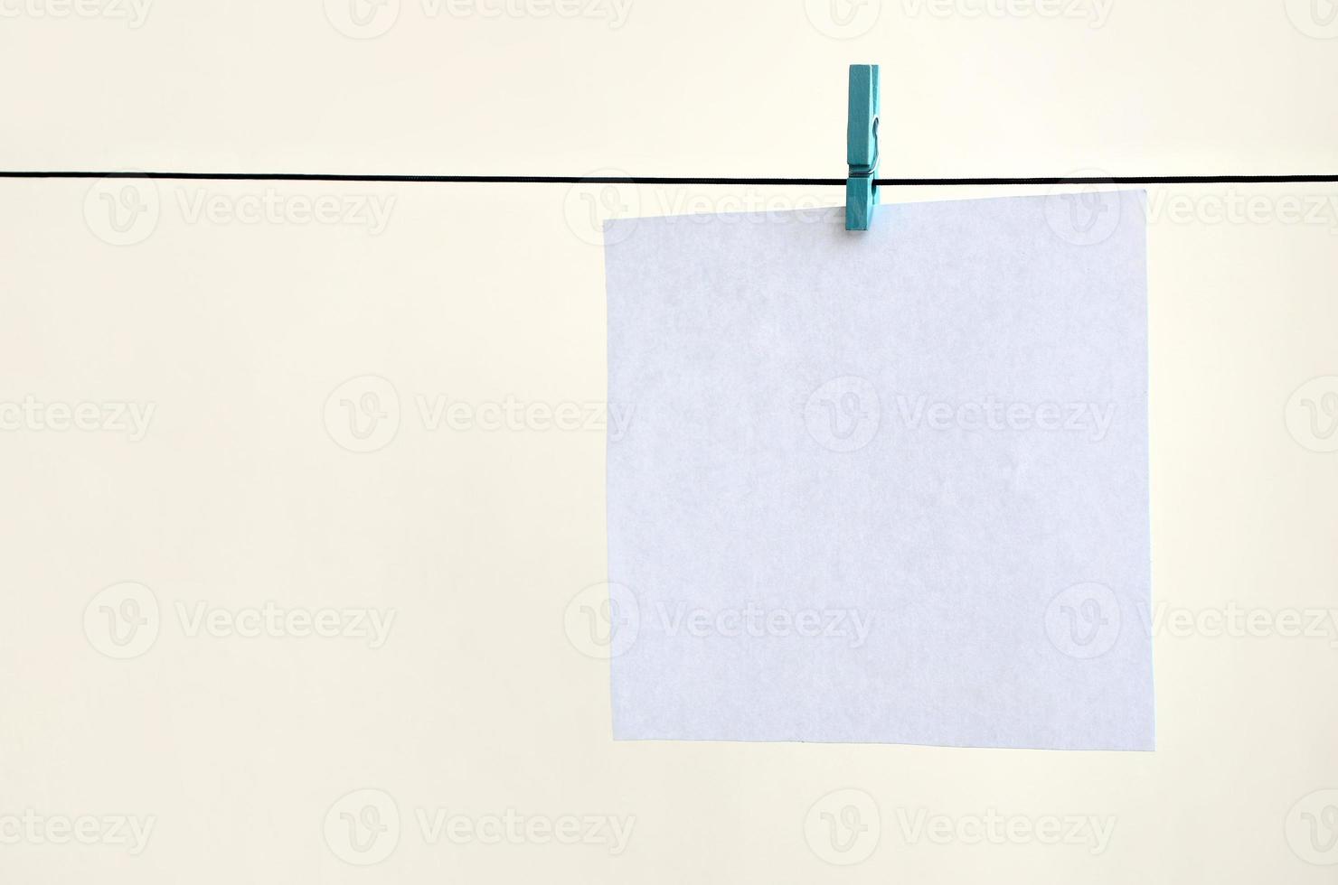 White blank cards on rope, light wall background. Creative reminder, small sheets of paper on old clothespin, memo backdrop photo