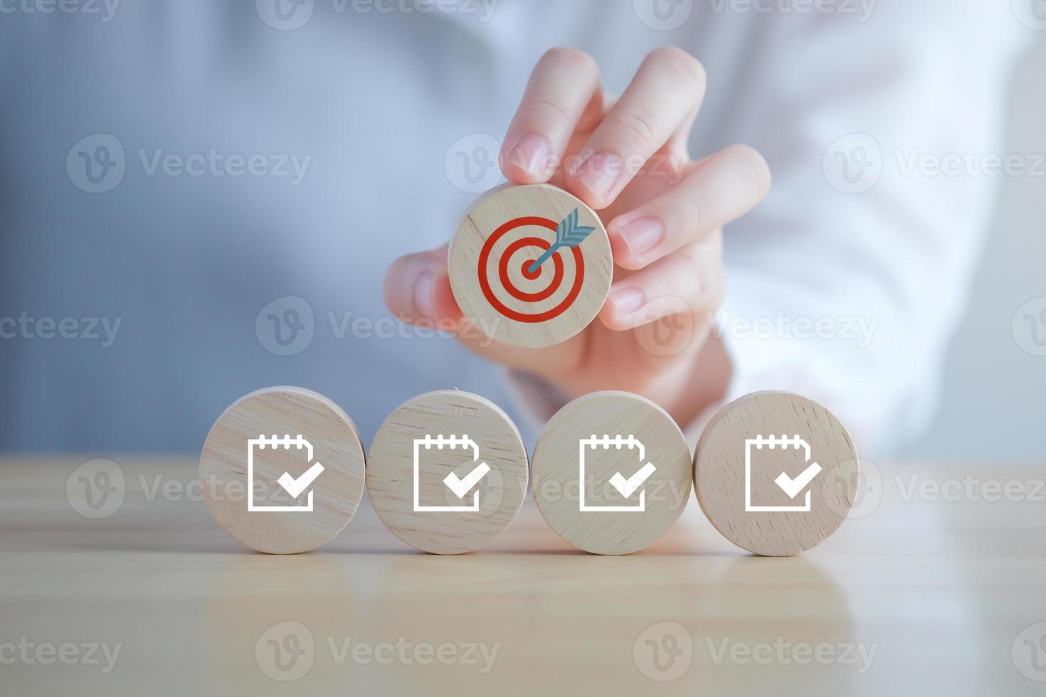 Checklist, Task list, Survey and assessment, Quality Control, Goals achievement and business success. to do list, Hand holding dartboard icon and checklist with check mark icon on wooden blocks. photo