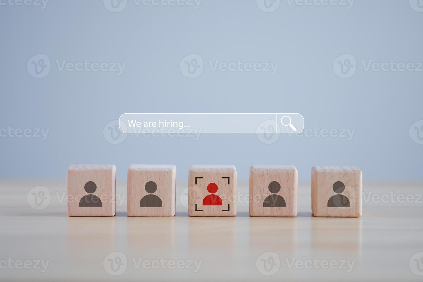 Business hiring and recruitment selection. Career opportunity. Human Resource Management. Magnifier glass on search bar with We are hiring text and red human icon among many human on wooden block. photo