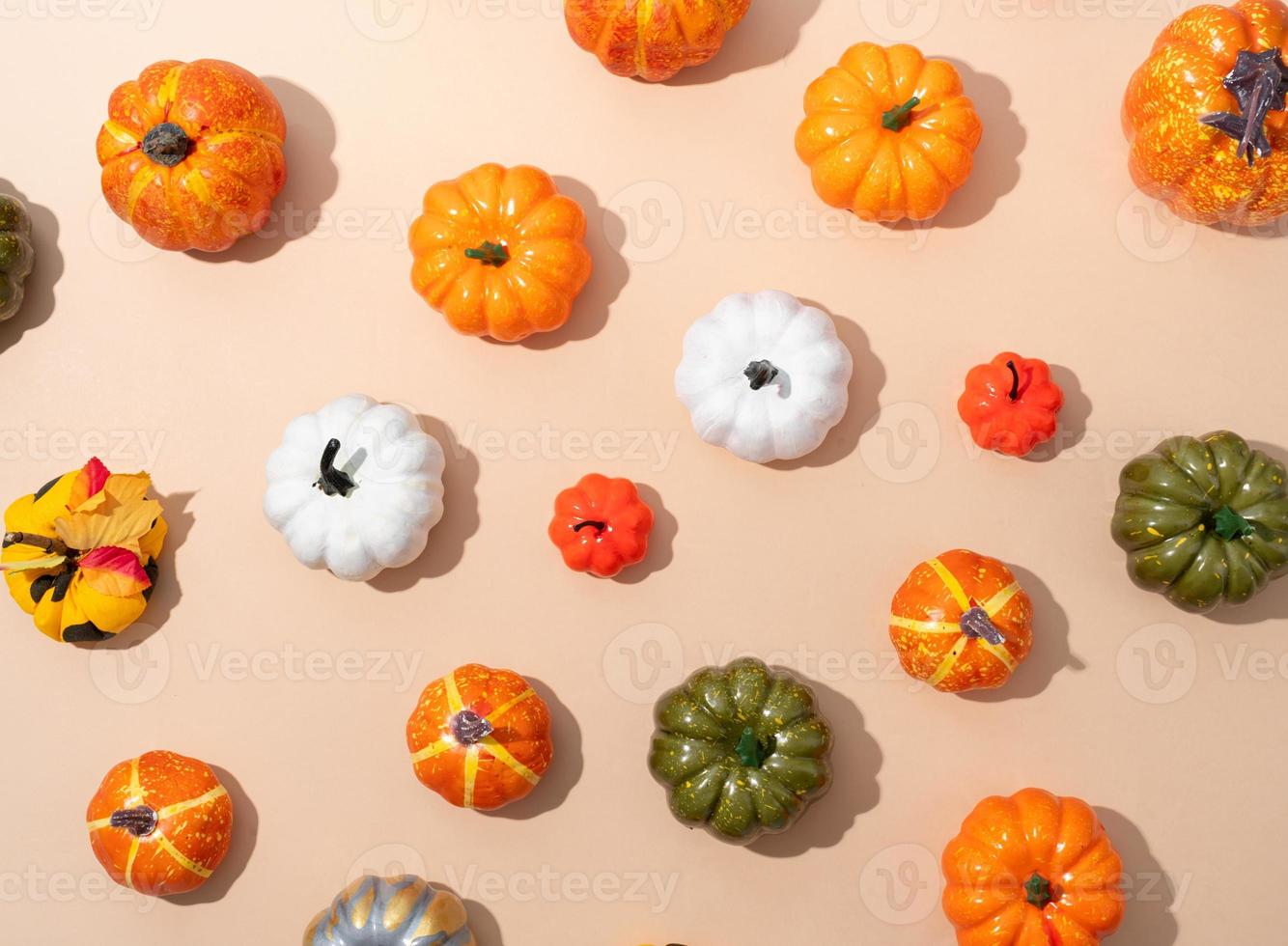 pattern of colorful artificial pumpkins on orange background photo