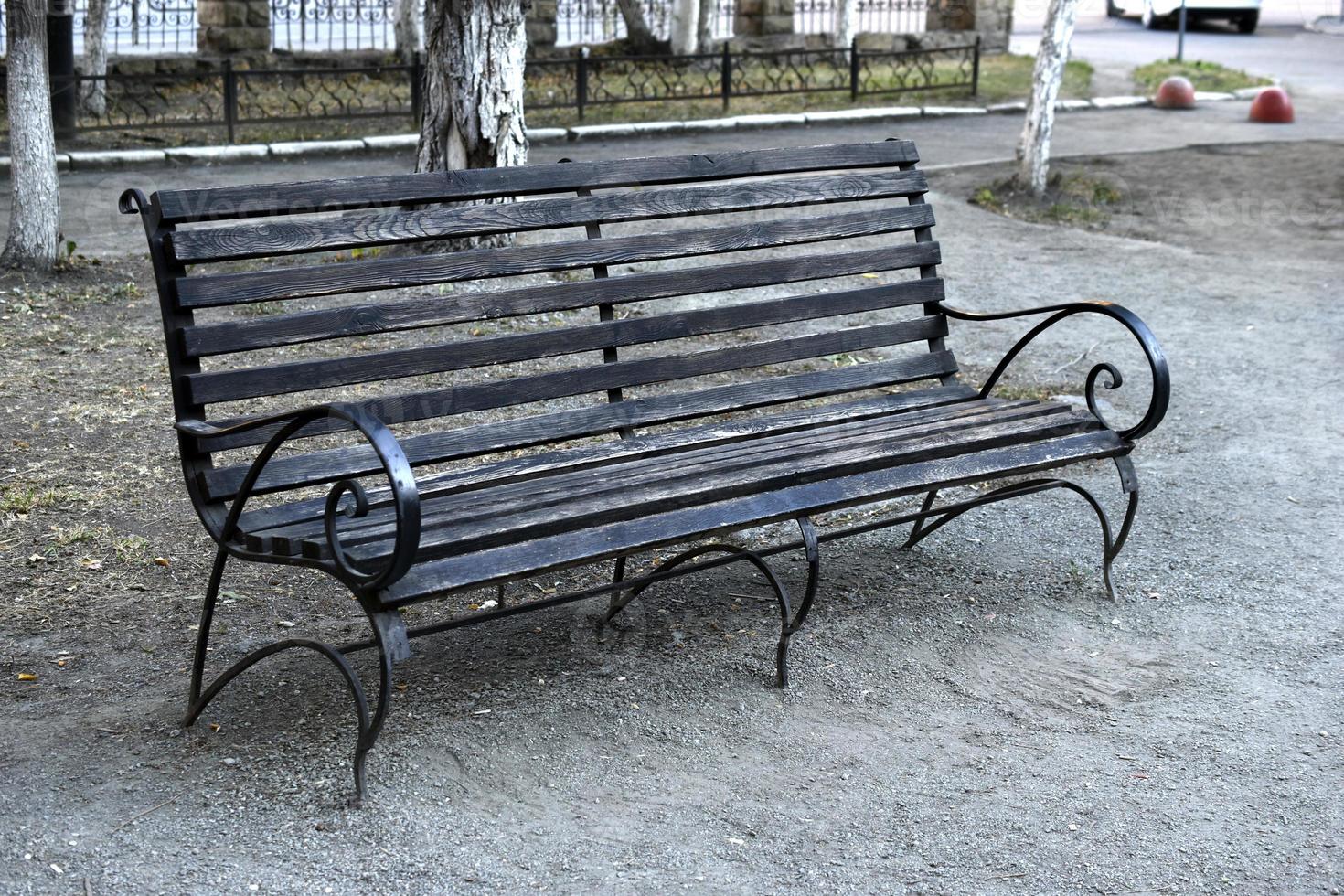 Wooden bench in a summer park in the city. Bench close-up in the afternoon. photo