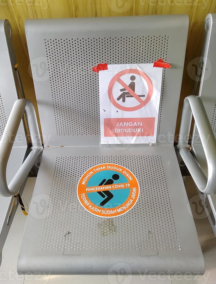 Iron chairs, in the hospital lobby. The seats are affixed with information stickers to maintain distance to prevent covid-19 infection. photo