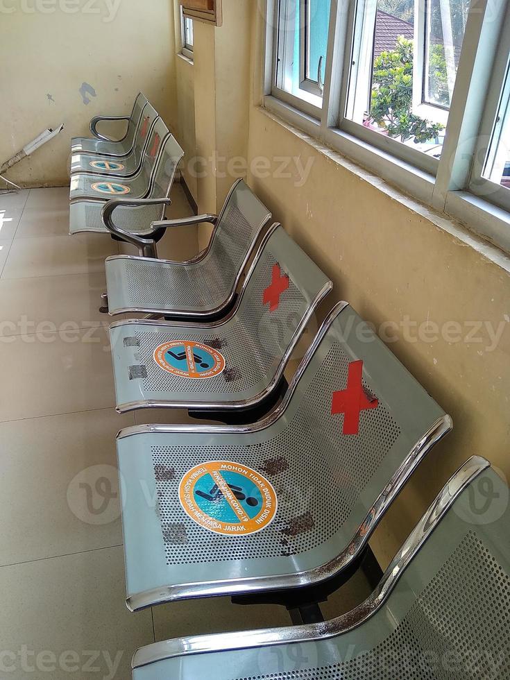 sillas de hierro, en el vestíbulo del hospital. los asientos están pegados con pegatinas de información para mantener la distancia y prevenir la infección por covid-19. foto