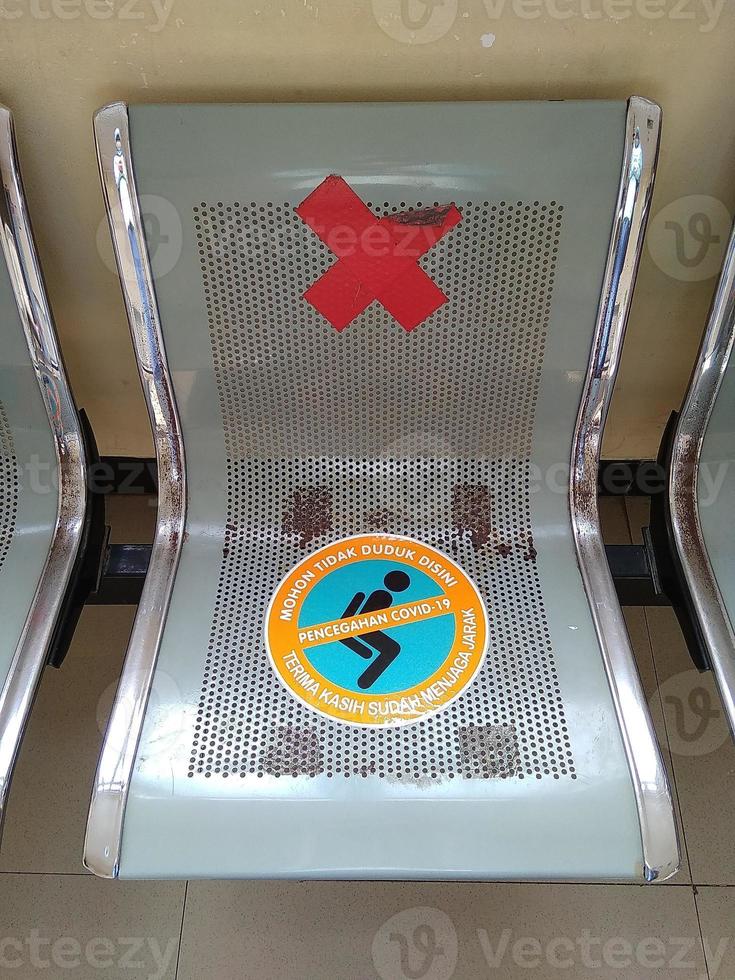 Iron chairs, in the hospital lobby. The seats are affixed with information stickers to maintain distance to prevent covid-19 infection. photo