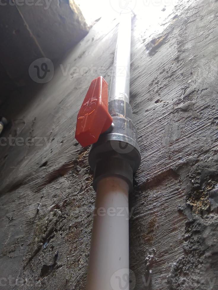 Water valve with red handle connect to PVC pipe photo