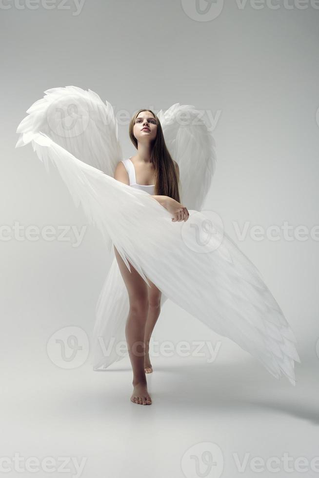una chica ángel romántica con un traje blanco con alas blancas foto