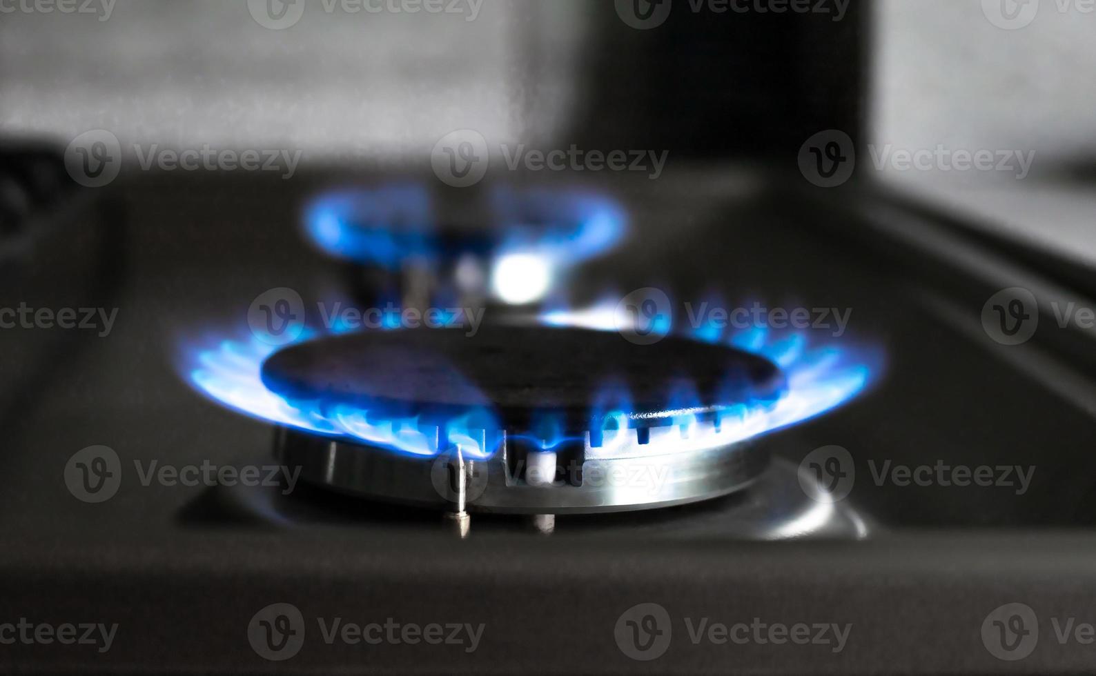 Close-up of a blue fire from a kitchen stove. two gas burners with a burning flame. economy concept photo