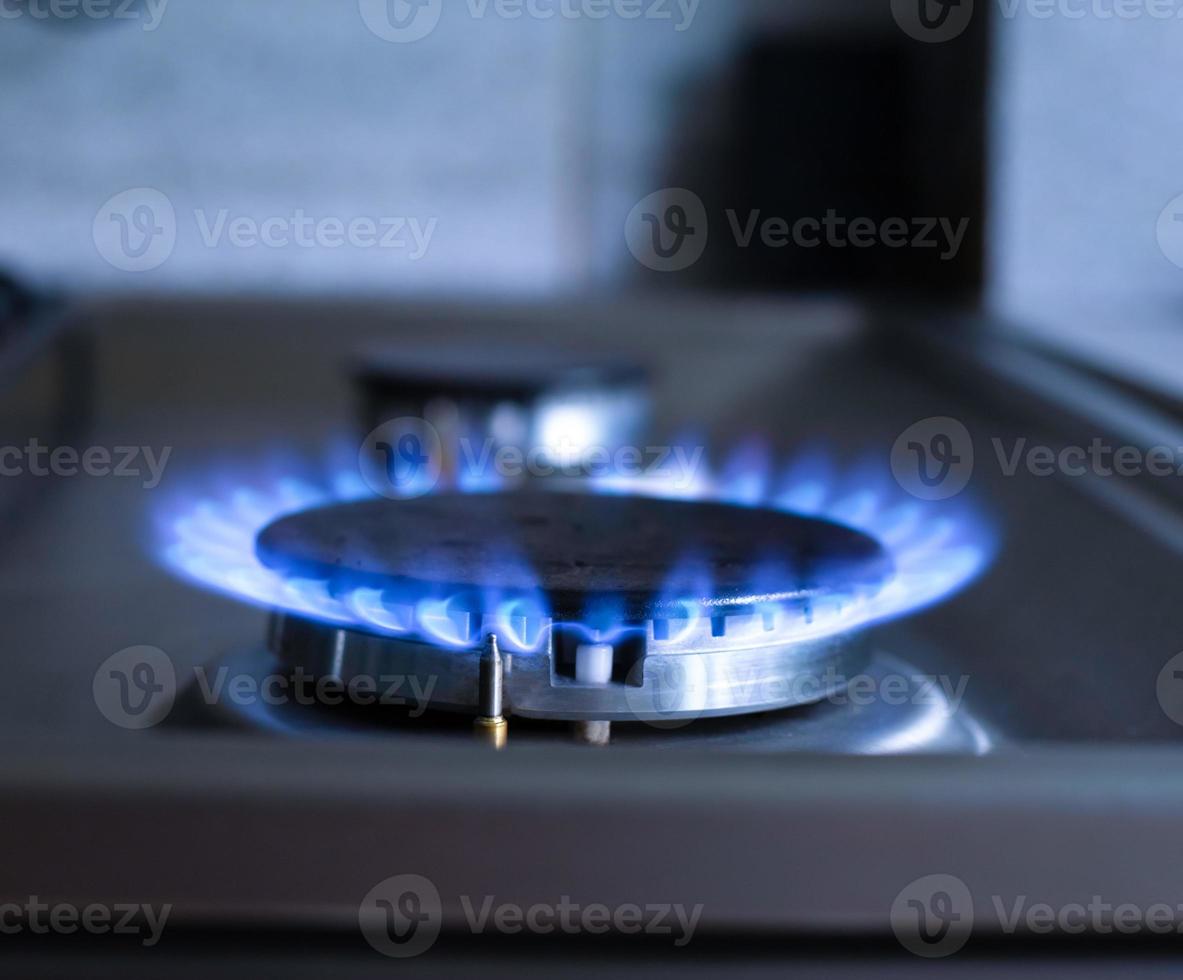 primer plano de un fuego azul de una estufa de cocina. quemador de gas con una llama ardiente. concepto de economía foto