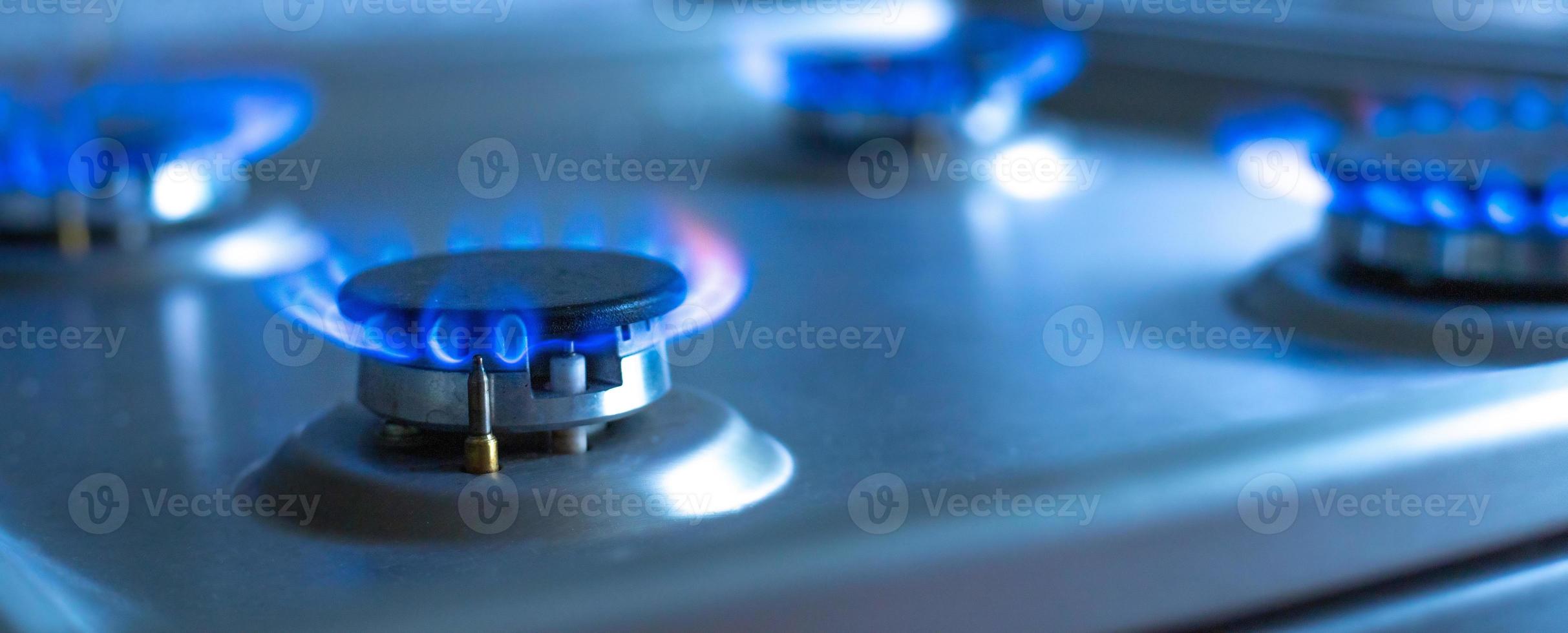 Close-up of a blue fire from a kitchen stove. 4 gas burners with a burning flame. economy concept. wide banner photo