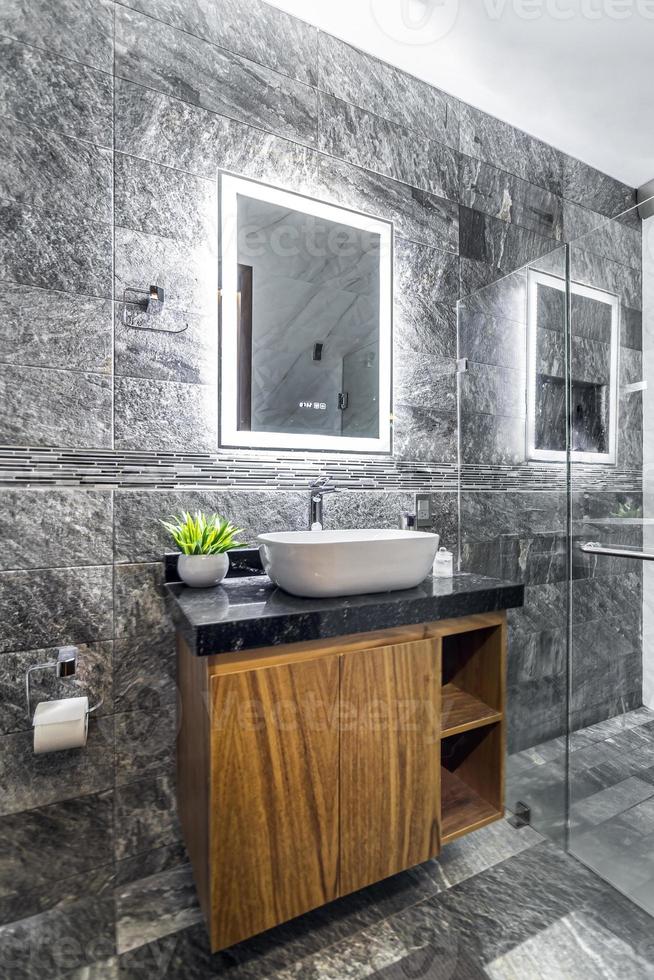 bathroom with luxury finishes, main mirror with led light from behind, white ceramic washbasin photo