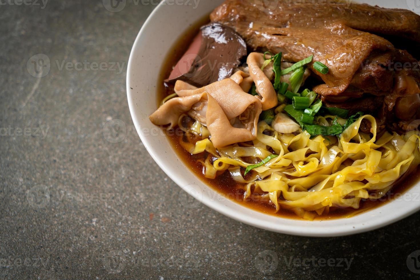 egg noodles with stewed and braised duck in brown soup photo