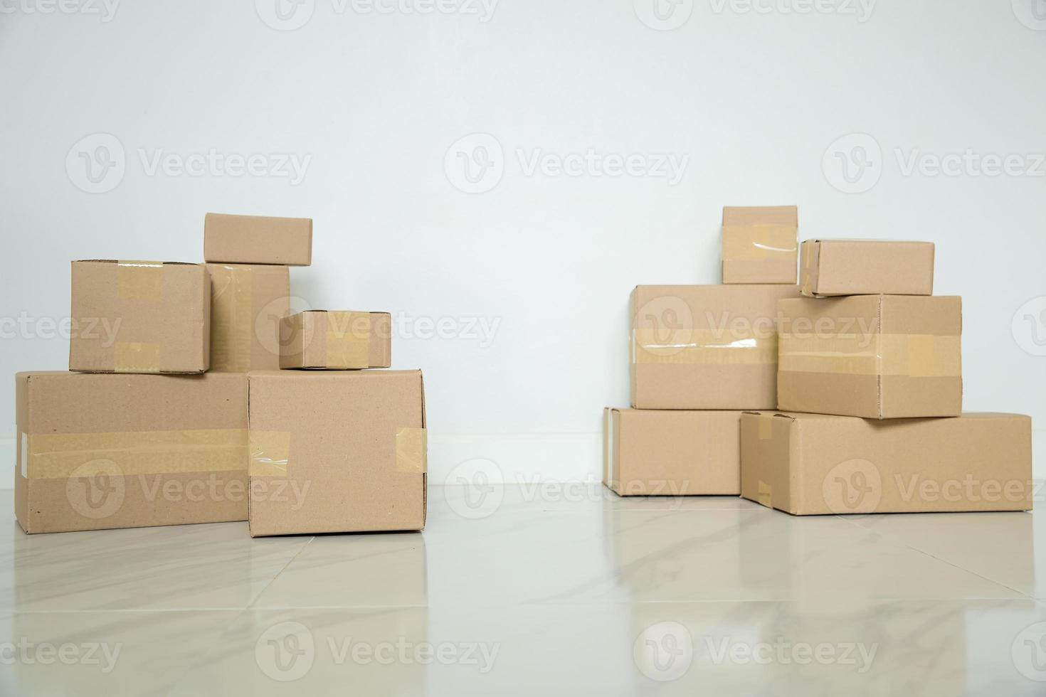 Stack of cardboard boxes for moving, Empty room with a white wall and cardboard boxes with unbranded barcode on the floor. Delivery of goods, shopping. Cardboard boxes on gray wall background. photo