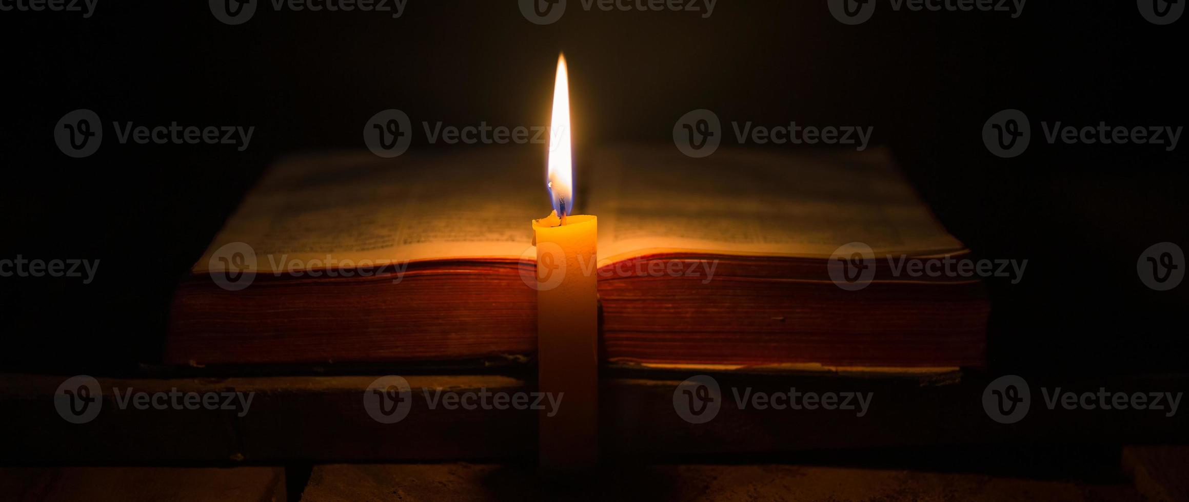 Light candle with holy bible and cross or crucifix on old wooden background in church.Candlelight and open book on vintage wood table christianity study and reading in home.Concept of christ religion photo
