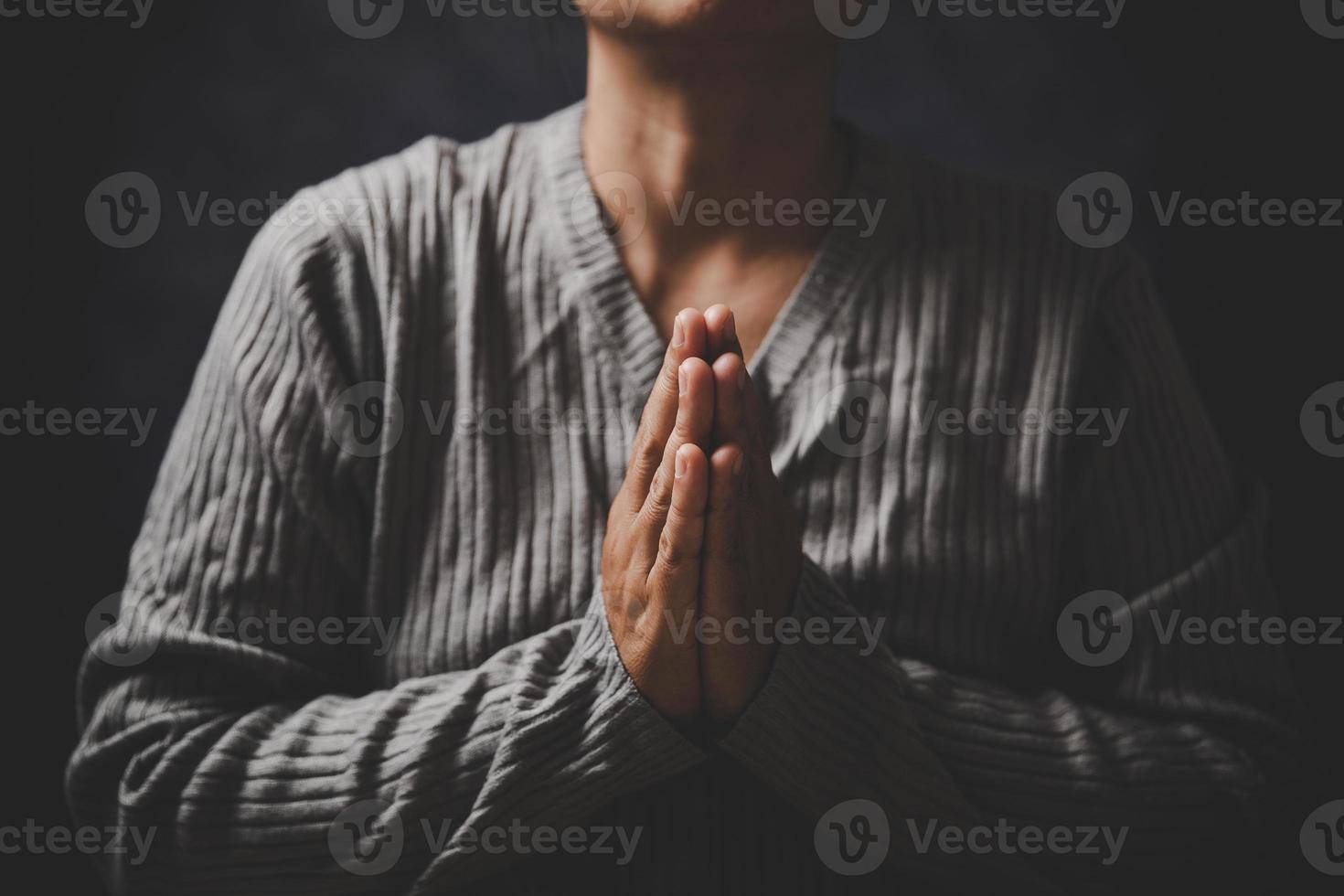 Christ religion and christianity worship or pray concept. Christian catholic woman are praying to god in dark at church. Prayer person hand in black background. Girl believe and faith in jesus christ. photo