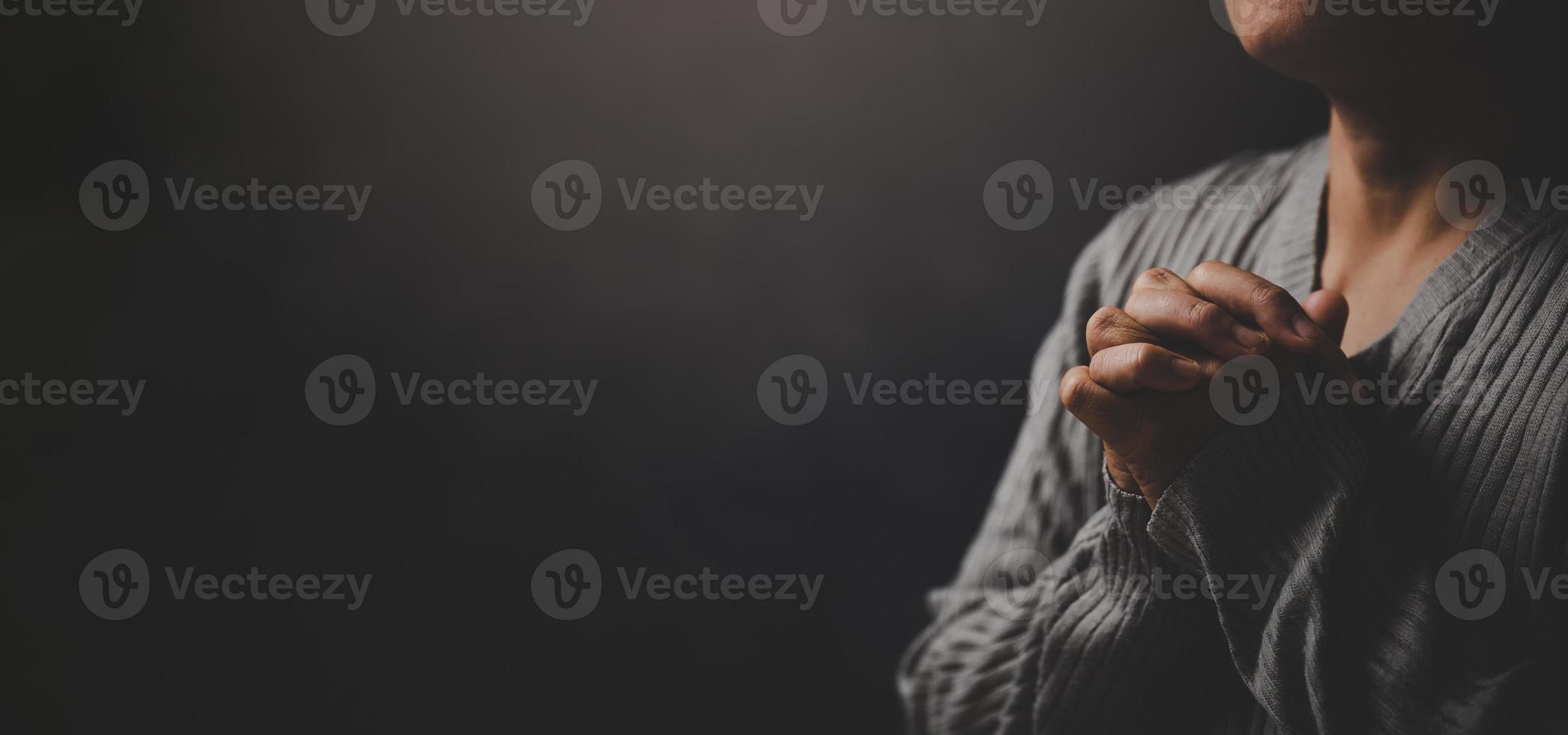 Christ religion and christianity worship or pray concept. Christian catholic woman are praying to god in dark at church. Prayer person hand in black background. Girl believe and faith in jesus christ. photo