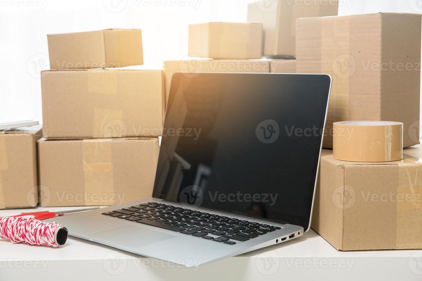 equipos para negocios en línea de pymes, computadoras portátiles de negocios de entrega, códigos de barras, cajas, verificación de productos en existencias o paquetes de cartón. pequeña empresa que trabaja en la oficina en casa. producto de servicio de entrega a domicilio. foto