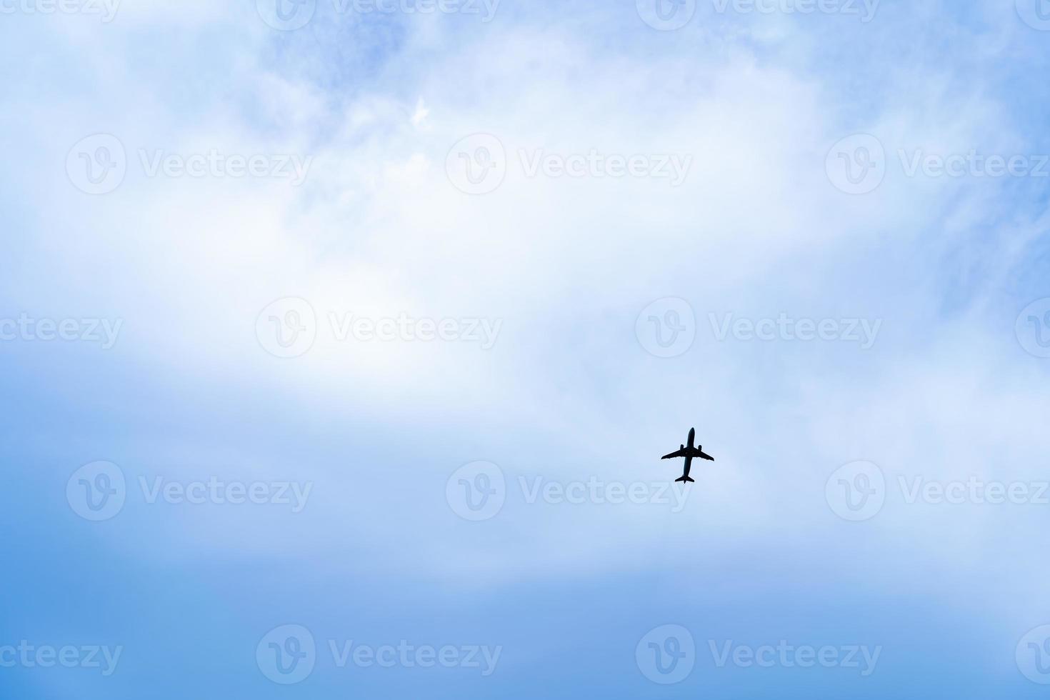 a silhouette airplane taking off and flying over the mountain with a blue-cloud sunny sky as background photo