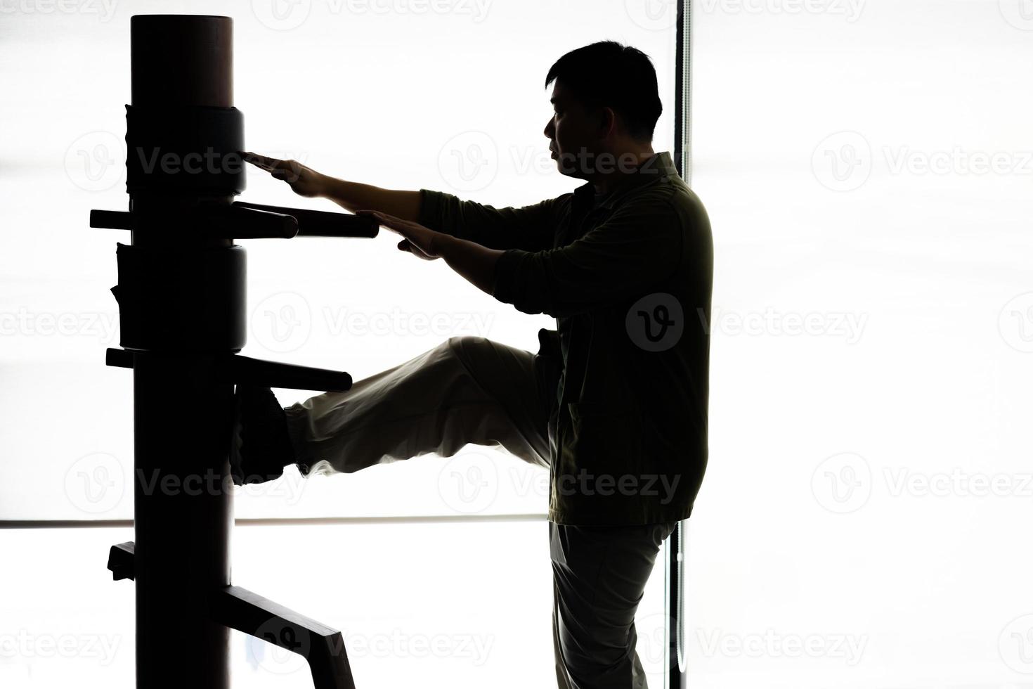 Silhouette of a fighter Wing Chun and wooden dummy on a background. Wing Chun Kung Fu Self defense photo