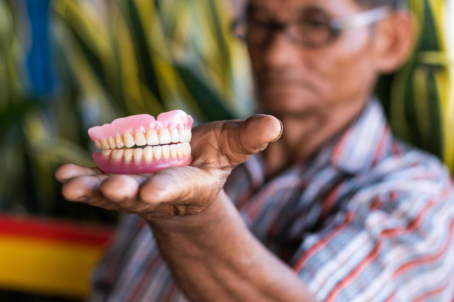 Dentures in the hands of elderly men in rural Thailand. photo