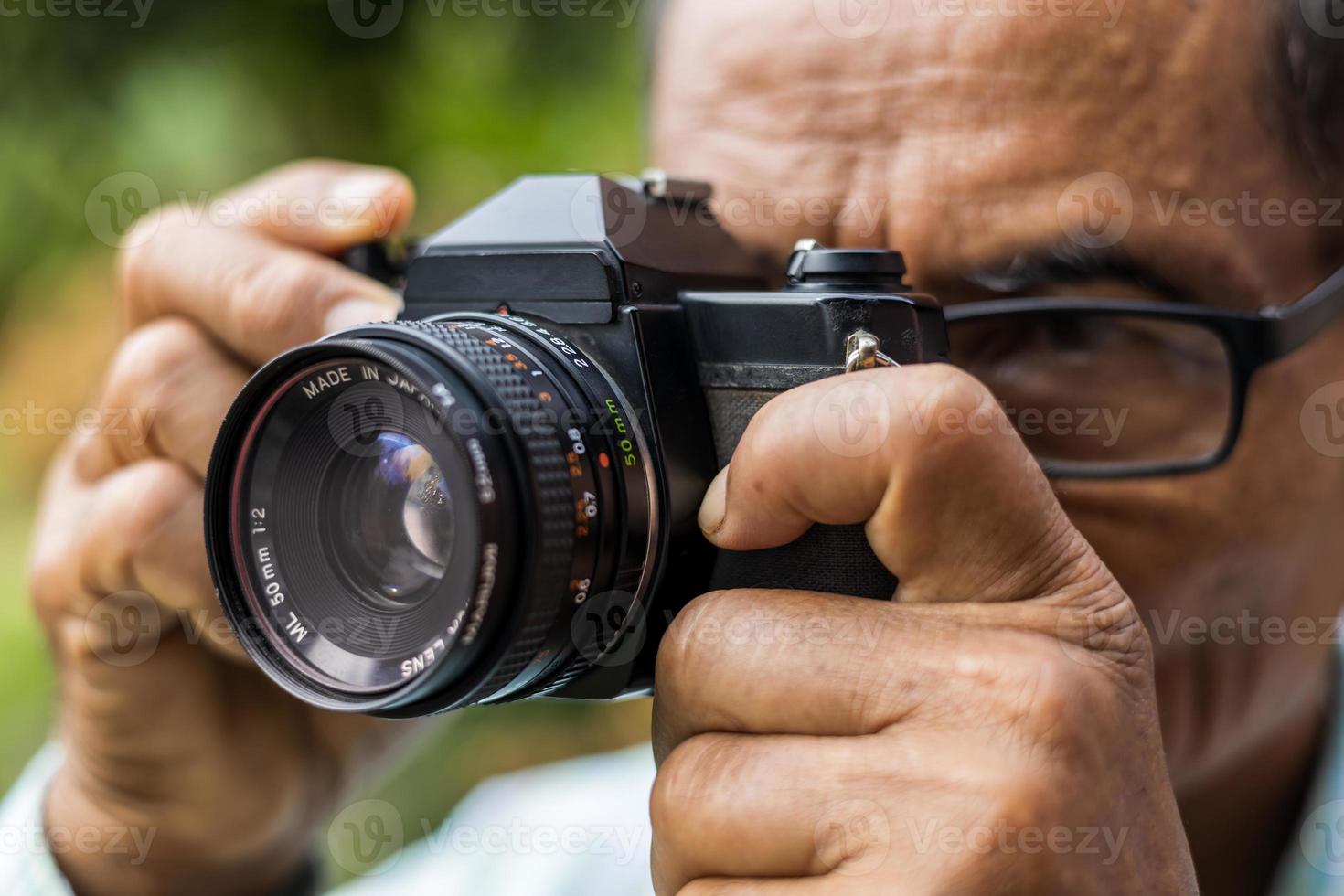 Close-up of an elderly man taking pictures with an old film camera. photo