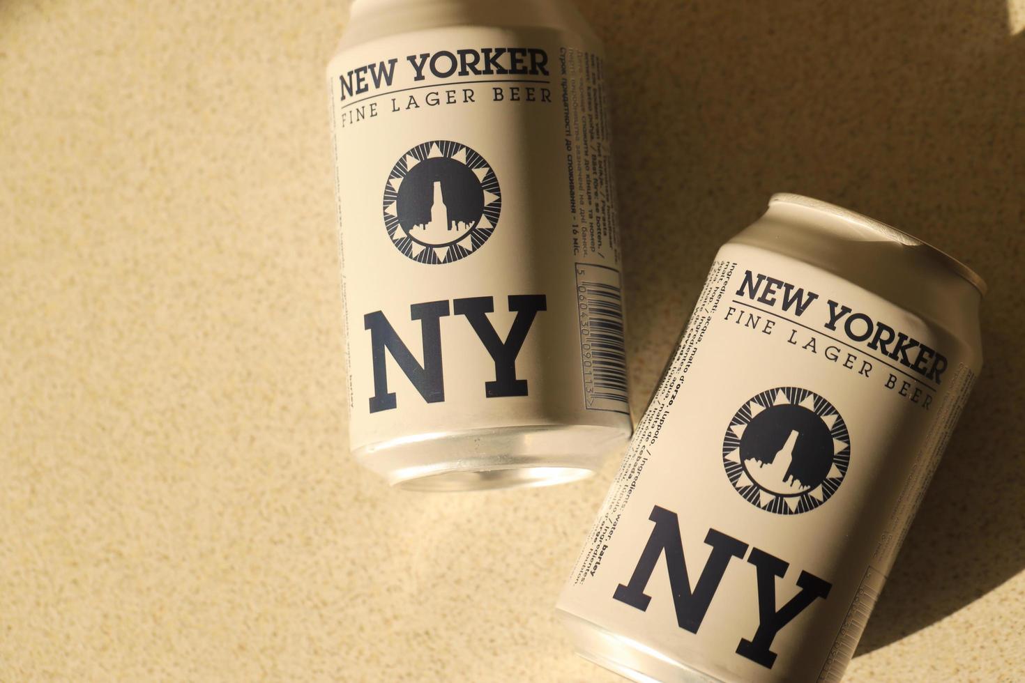 TERNOPIL, UKRAINE - JULY 18, 2022 Two cans of New Yorker fine lager beer with original logo and design on brown retro background photo