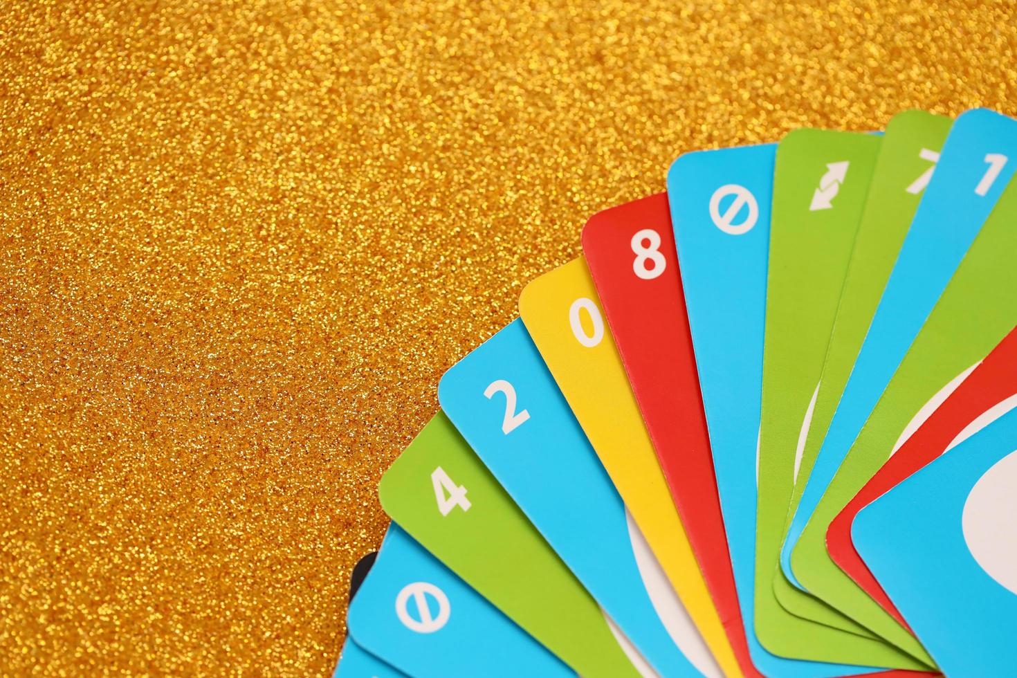TERNOPIL, UKRAINE - MAY 15, 2022 Many colorful UNO game cards on golden background. UNO is an American shedding-type card game that is played with a specially printed deck photo