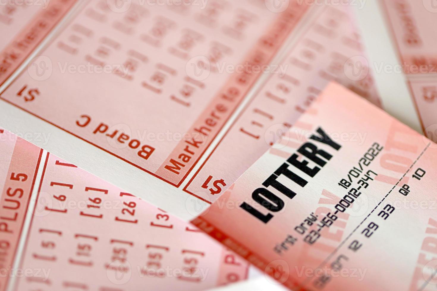 Red lottery ticket lies on pink gambling sheets with numbers for marking to play lottery. Lottery playing concept or gambling addiction. Close up photo