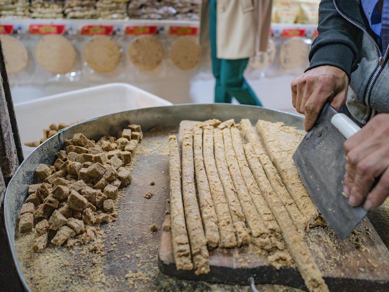 Cutting Sweet Peanuts Stick with clever knife in souvenir shop of  fenghuang old town photo